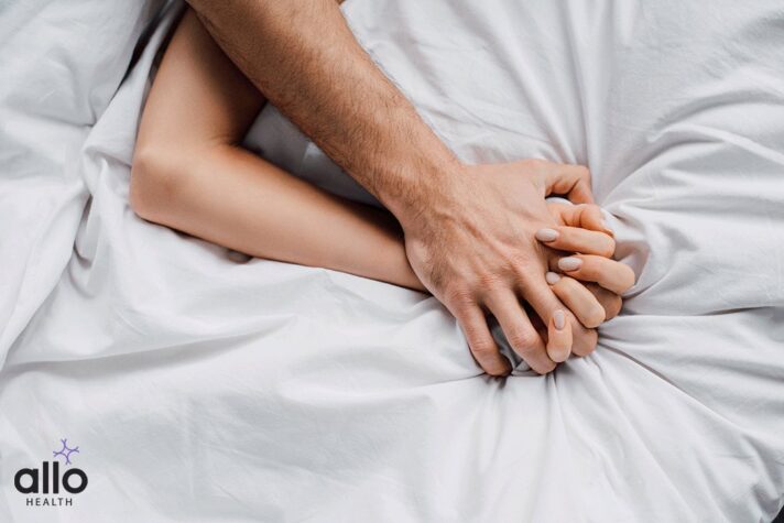 Top view of woman holding hand of boyfriend on bed