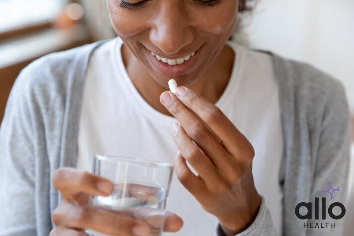 Close up happy young african american young woman taking daily dose of Metronidazole