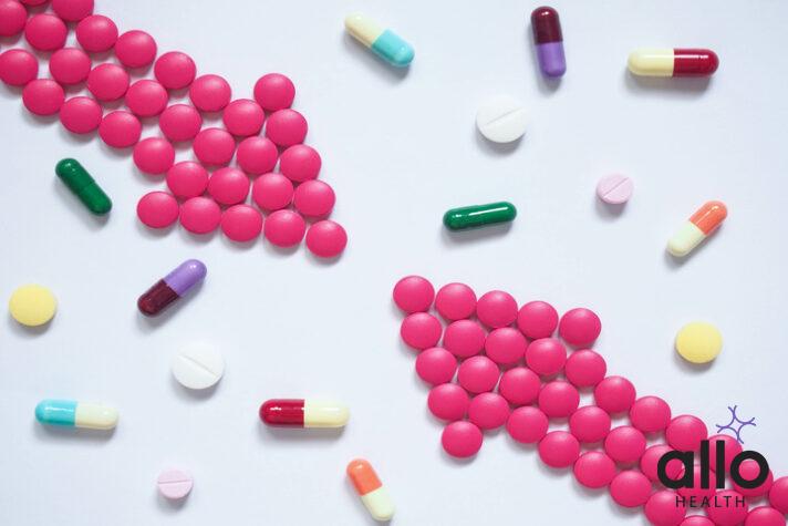 Two pink arrows made by pills among many different medical table