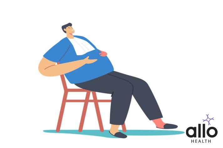 Fat Overeat Man with Napkin on Chest Sitting on Chair Flapping Belly with Hands and thinking about Health Risks & Chronic Disease That Can Cause Obesity