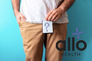 A man in beige jeans holds a notepad with question mark. Close up. Blue background. The concept of artificial insemination and impotence. does masturbation affect muscle gains