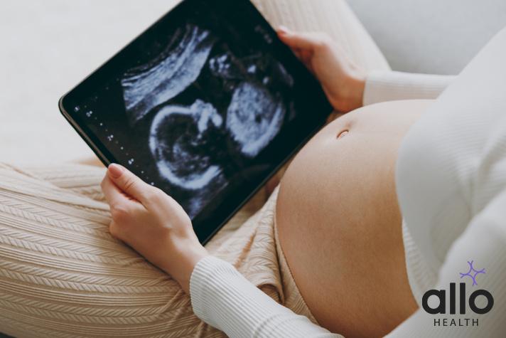 Cropped close up young pregnant woman wears white pyjamas hold in hand picture of ultrasound examination rest relax spend time in bedroom lounge home. Maternity family pregnancy expectation concept. aua meaning in pregnancy